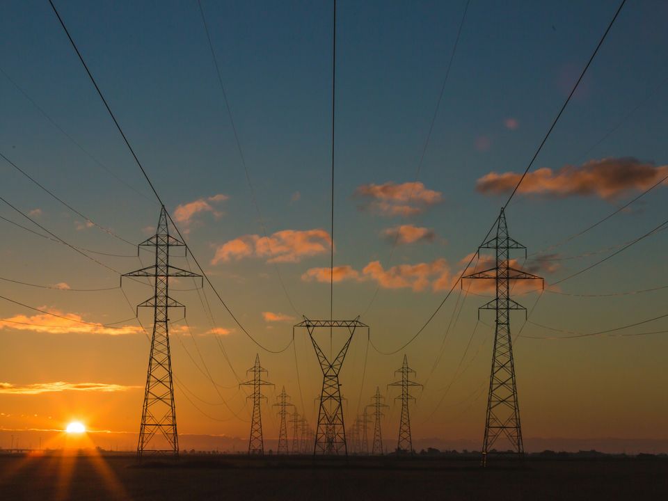 Transmission towers carrying overhead power lines at sunset