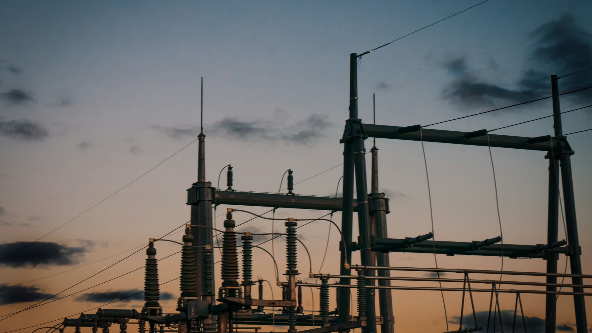 High-voltage switchyard with transformers and insulator stacks at dusk