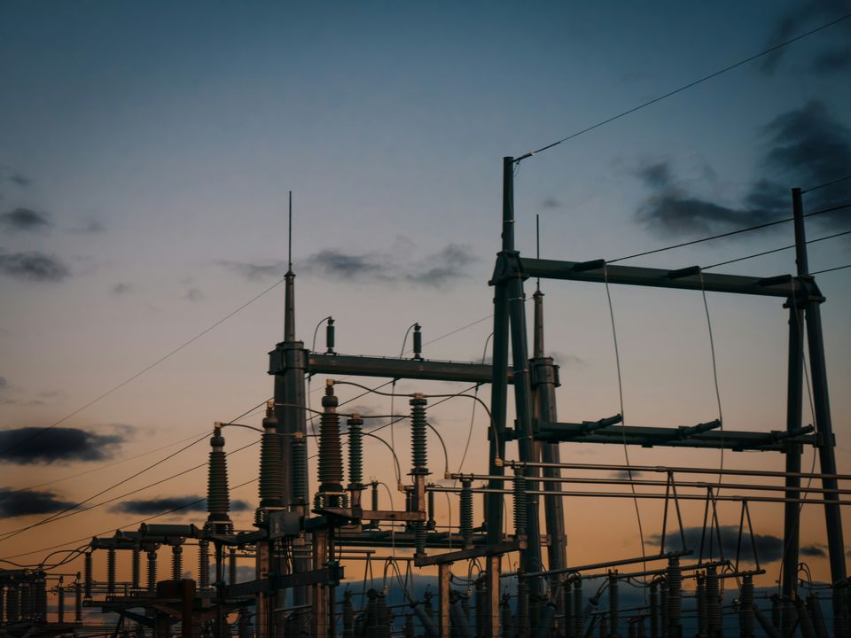 High-voltage switchyard with transformers and insulator stacks at dusk
